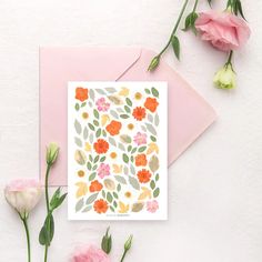 a card with an orange and pink flower pattern on it next to some pink flowers