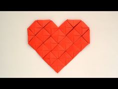 an origami heart made out of red paper on a white surface with the shape cut into smaller squares