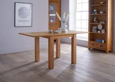 a wooden table sitting on top of a hard wood floor next to a book shelf