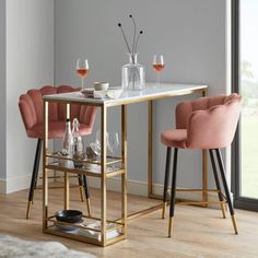 two pink chairs sitting at a table with wine glasses on it