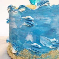 a blue cake with white frosting and gold sprinkles