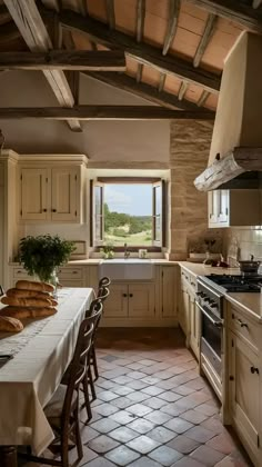 a kitchen with an oven, table and chairs next to a window that looks out onto the countryside