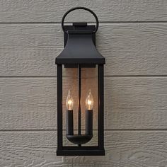 an outdoor wall light with three candles on it