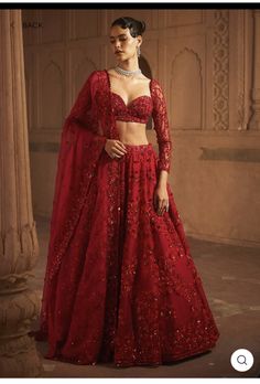 a woman in a red gown standing next to pillars