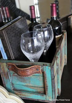 three wine glasses in an old wooden crate with books and other items on the table