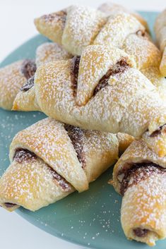 several pastries on a blue plate with powdered sugar sprinkled around them