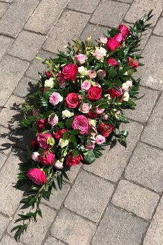 a bouquet of flowers is laying on the ground in front of a brick wall and sidewalk