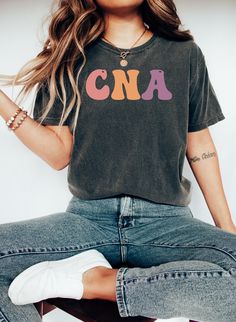 "Comfort Colors CNA Shirt, Retro CNA T-shirt, Personalized CNA Tee, Certified Nursing Assistant T-shirt, Custom Nurse T-shirt, Women Shirt https://toptrendtshirtsus.etsy.com NOTE: Please contact me for more size,color, product (sweatshirt, hoodies,kids etc) options. I'm always here to help. Unisex Garment-Dyed T-shirt Comfort Colors® 1717 *Medium fabric (6.1 oz/yd² (206.8 g/m *Relaxed fit *Sewn-in twill label *100% ring-spun cotton About Comfort Colors introduces its garment-dyed t-shirt; a fully customizable tee made 100% with ring-spun cotton. The soft-washed, garment-dyed fabric brings extra coziness to your wardrobe while the relaxed fit makes it an excellent daily choice. The double-needle stitching throughout the tee makes it highly durable while the lack of side-seams helps the shir Fun Short Sleeve Letter Print T-shirt, Tri-blend Pre-shrunk Graphic Tee, Casual Multicolor T-shirt With Funny Print, Casual Tri-blend Tops With Letter Print, Retro Soft-washed Crew Neck T-shirt, Basic Crew Neck Top With Funny Print, Vintage Style Tri-blend Tops With Letter Print, Casual Tri-blend Shirt With Text Print, Multicolor Letter Print Tops With Relaxed Fit