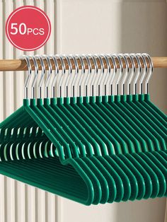 there are several green hangers on the clothes rack and one has a red sign that says 50 pcs