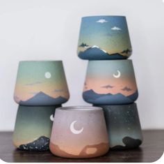 four painted cups sitting on top of a wooden table