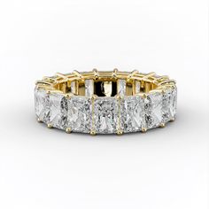 a yellow gold ring with princess cut diamonds on the sides and four prongs