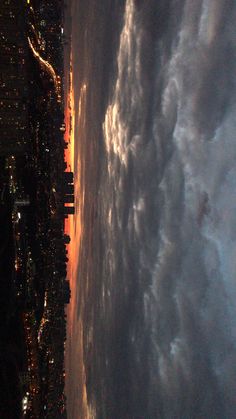 the view from an airplane looking down at clouds and city lights