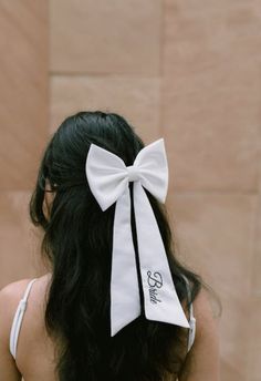 a woman with long black hair wearing a white bow