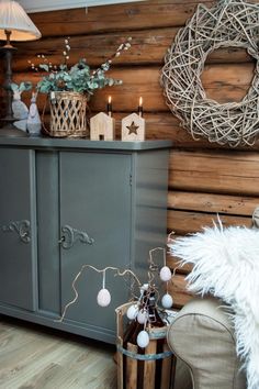 a gray cabinet sitting next to a wooden wall with wreaths on top of it