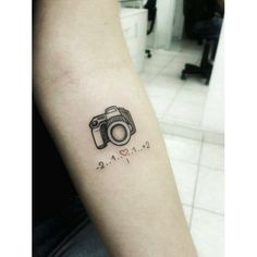 a small camera tattoo on the arm