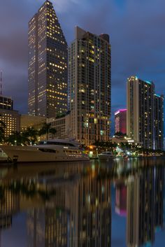 the city is lit up at night and reflecting in the water