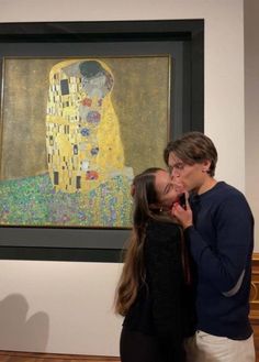 two people standing next to each other in front of a painting