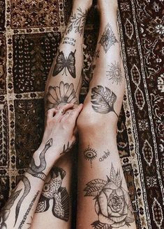 two women with tattoos on their legs laying down