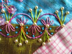 three embroidered flowers and pearls on a piece of fabric with pink gingham checkered table cloth