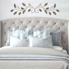 a bed with pillows and decorative metal wall art above the headboard in a bedroom