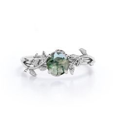 a ring with an oval green stone surrounded by leaves on the side and diamond accents