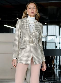 a woman is standing in front of a chair wearing a jacket and pants with high heels