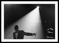 a black and white photo of a man on stage with his arms out to the side