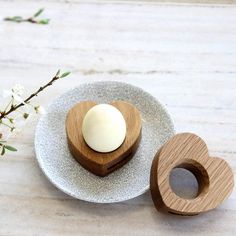 two wooden heart shaped dishes sitting on top of a white plate next to each other