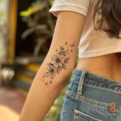 a woman's arm with flowers and stars tattoo on the left side of her right arm