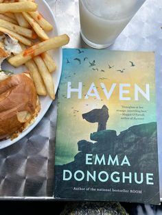 a book sitting on top of a table next to a plate of fries and a sandwich