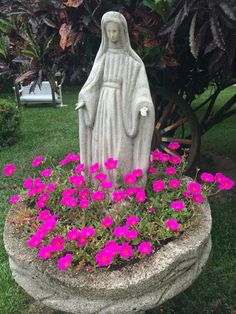 a statue in a flower pot with pink flowers