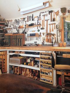 a workbench with many tools hanging on the wall and shelves full of tools