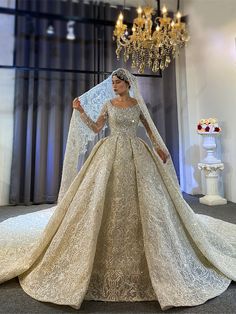 a woman in a wedding dress with a veil on her head standing next to a chandelier