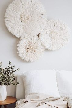 a white bed with pillows and blankets on top of it next to a vase filled with flowers