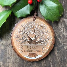 a wooden ornament with a christmas tree on it and holly leaves around it