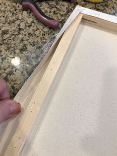 someone is working with wood to make a frame for a painting on the counter top