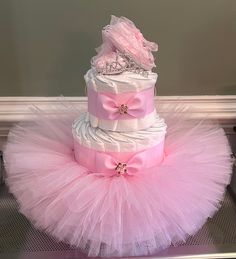 a pink and white diaper cake sitting on top of a metal pan covered in tulle