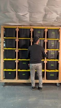 a man standing in front of a shelf filled with plastic bins