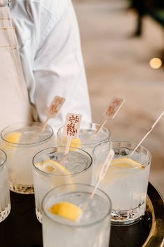 four glasses with lemons in them sitting on a tray