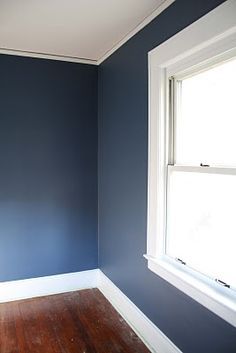 an empty room with blue walls and wood floors