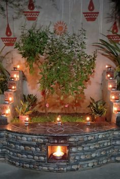 an outdoor fire pit with candles lit in the center and greenery on either side