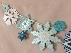 paper snowflakes are hanging from a clothes line on a table with other decorations