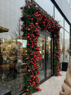 a christmas wreath on the side of a store front window decorated with red berries and greenery