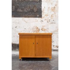 a wooden cabinet sitting in front of a brick wall