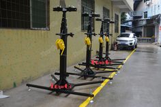 four black and yellow bicycle racks on the side of a building in front of a white car