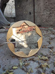 a mirror that is on the ground in front of a brick wall and some leaves