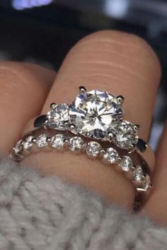 a woman's hand with two engagement rings on top of her finger and the ring is