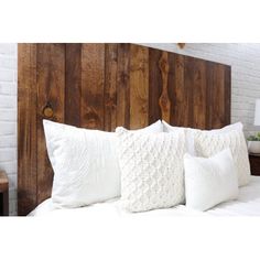 a bed with white pillows and wooden headboard