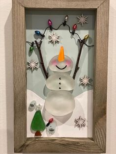 a snowman with an orange hat is in a shadow box