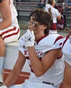 a football player sitting on the sidelines with his face painted